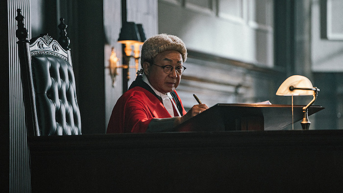A judge in traditional robe and wig writes notes at the bench in a courtroom scene from The Prosecutor (2024).