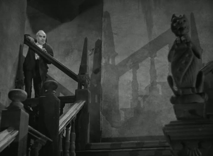  Black-and-white still from The Old Dark House (1932) showing an eerie staircase with dramatic shadows and an elderly man standing at the banister. Gothic horror atmosphere captured in sharp detail.