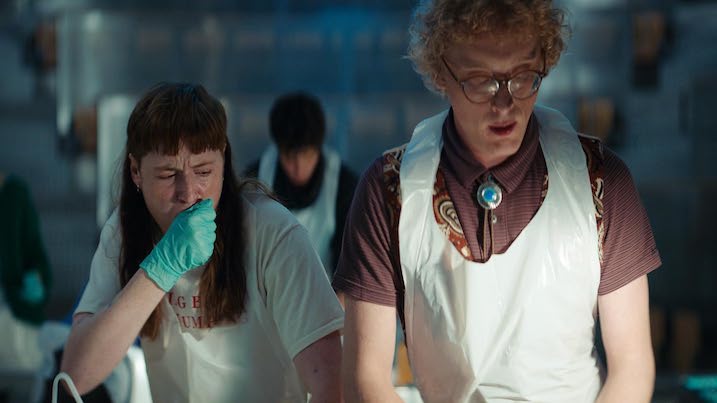 Two medical students examine a body during an autopsy training session in Nightwatch Demons are Forever, reacting with discomfort.