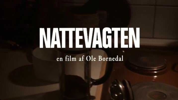 Opening title card for Nattevagten (Nightwatch) in Danish, with ‘en film af Ole Bornedal’ written below in a dimly lit kitchen scene.
