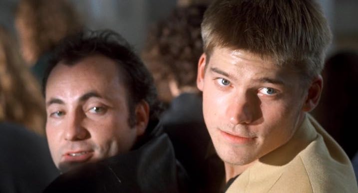 Scene from Nightwatch (1994) showing young Nikolaj Coster-Waldau glancing over his shoulder with Kim Bodnia in the background.