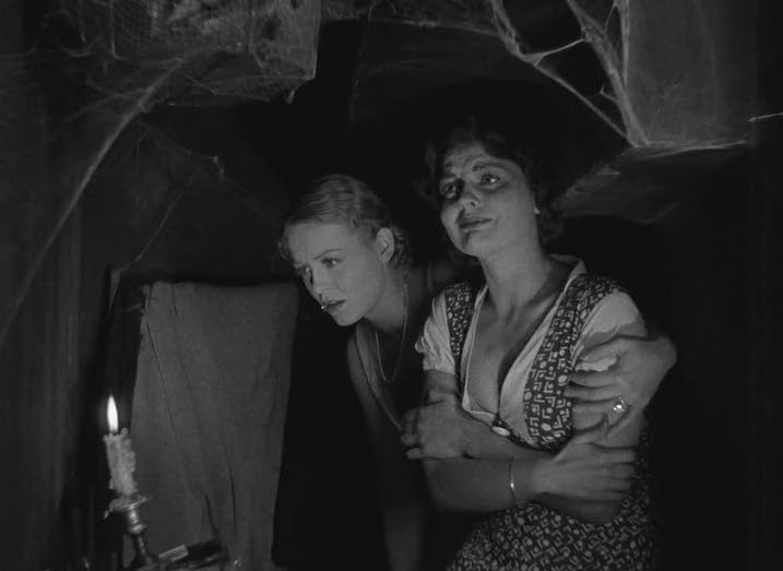  Two women hiding in a cobwebbed secret passageway in The Old Dark House (1932), illuminated only by a flickering candle. Classic horror suspense captured in chiaroscuro lighting.