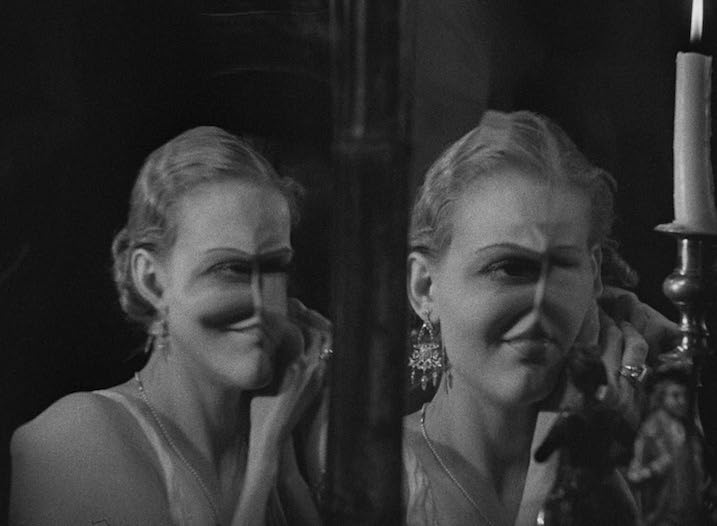  Haunting mirror reflection scene from The Old Dark House (1932), showing a woman's face eerily distorted by glass. A surreal moment of psychological unease within the pre-Code horror classic.