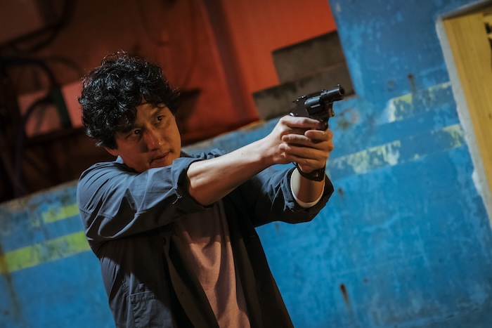 A disillusioned detective aiming his pistol in Yadang: The Snitch, the South Korean action crime film from Well Go USA.