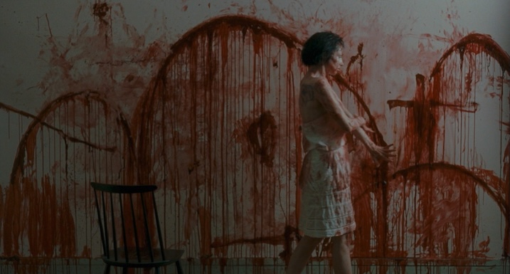 Béatrice Dalle in Trouble Every Day, standing in front of a wall covered in smeared blood.
