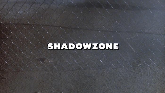 Opening title card from Shadowzone showing the film’s logo against a chain-link background.