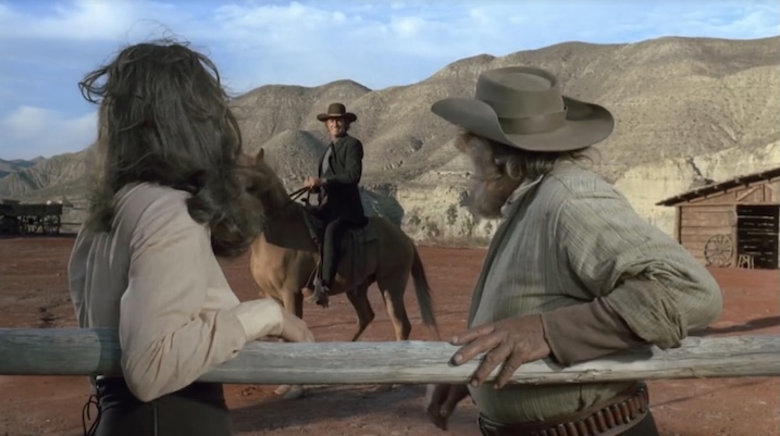 The Man Called Noon (1973) showing Richard Crenna on horseback approaching two characters at a ranch fence, with desert mountains in the background.