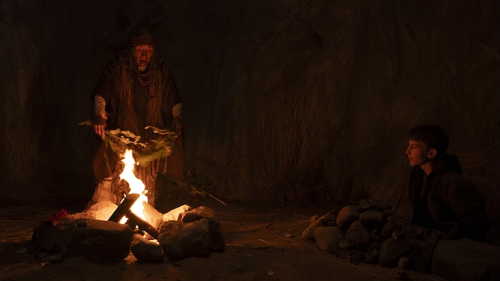 Image 2: A shaman performs a ritual by firelight while the missionary’s son watches in Shaman (2025), highlighting the clash between indigenous tradition and outside faith.